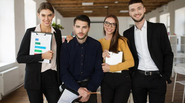 group-young-smiling-business-people-classic-suits-joyfully-looking-camera-together-while-spending-time-work-modern-office_574295-5897